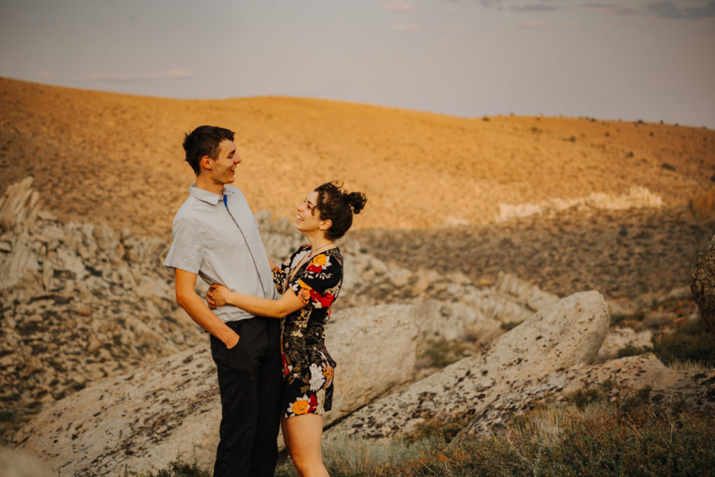 couple looking at each other with sunset light in background.